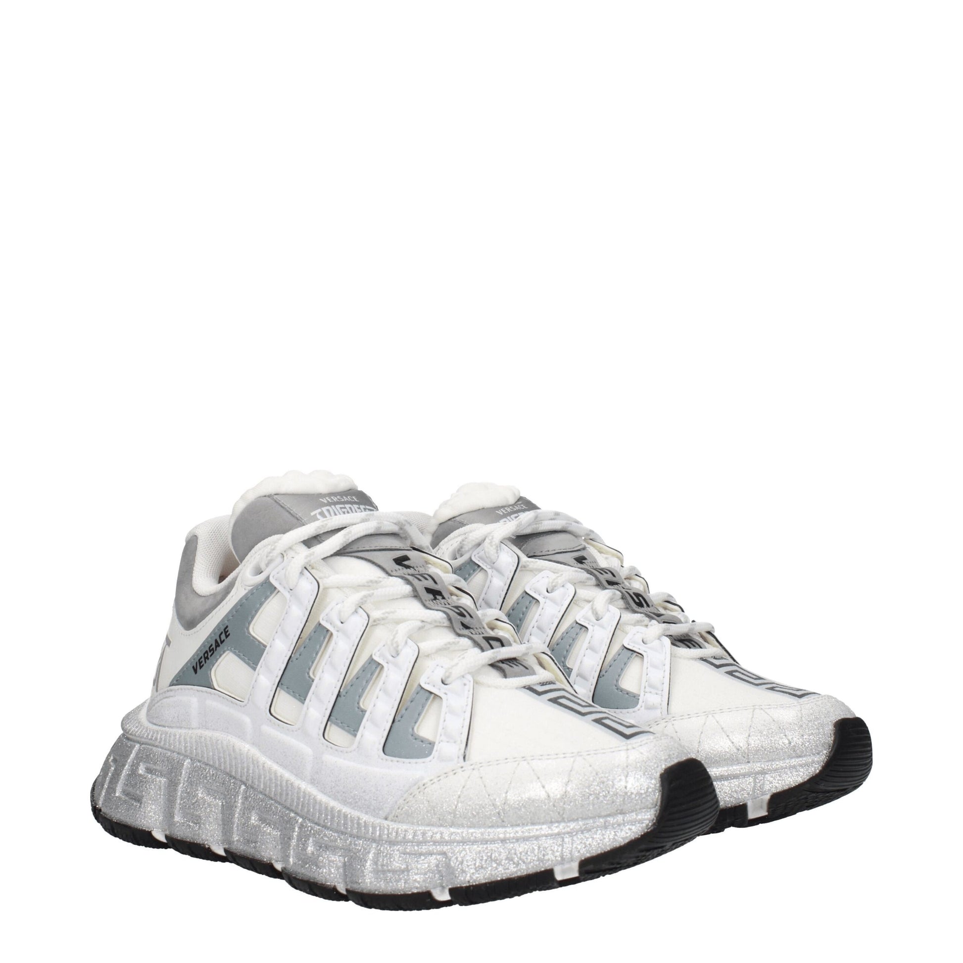A pair of white athletic sneakers with silver accents, featuring a lace-up design and a textured sole