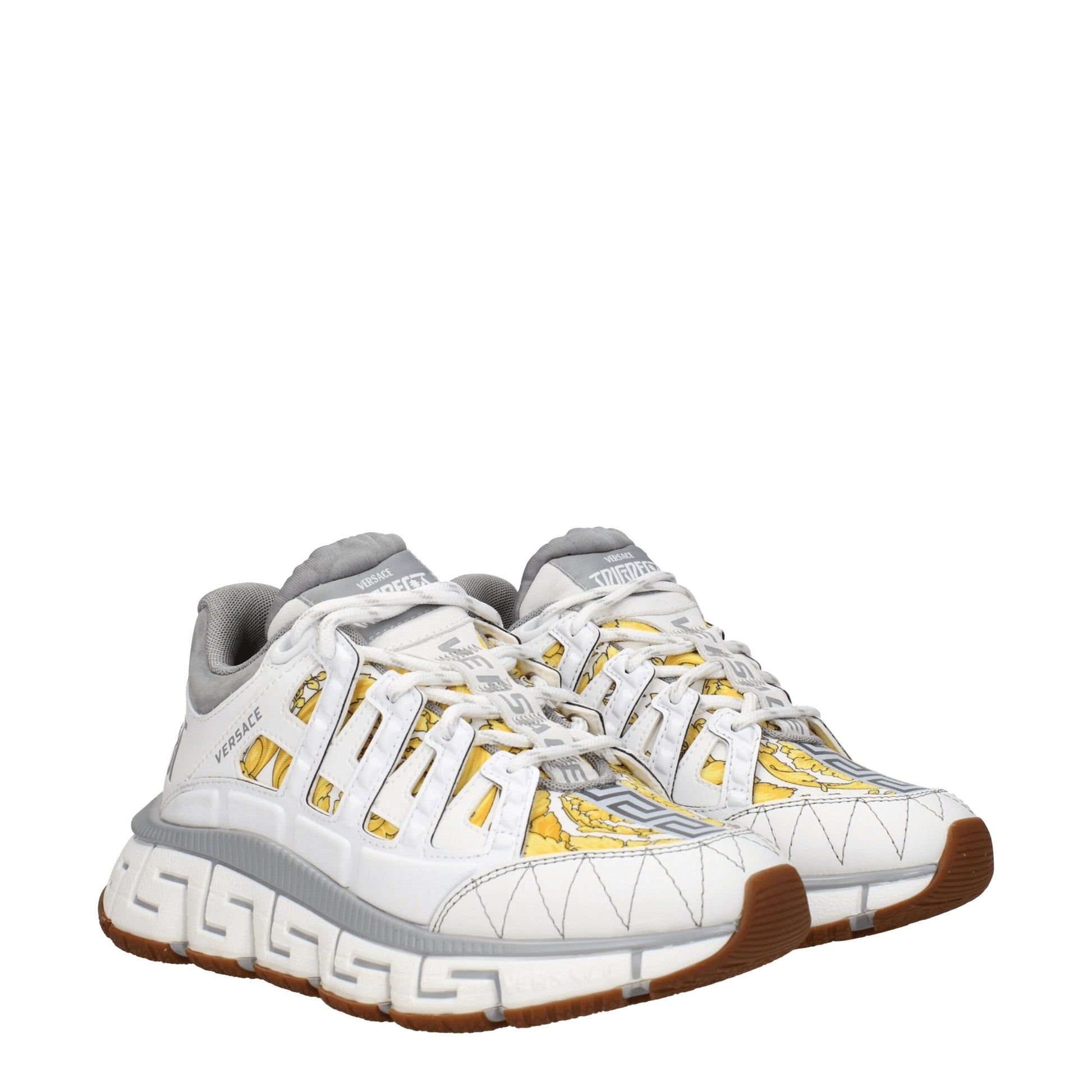 White athletic sneakers with yellow accents and brown soles, featuring a logo on the side